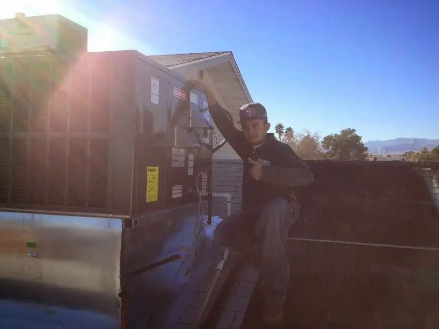 HVAC technician performing Heat Pump Repair on a rooftop unit in Palmer